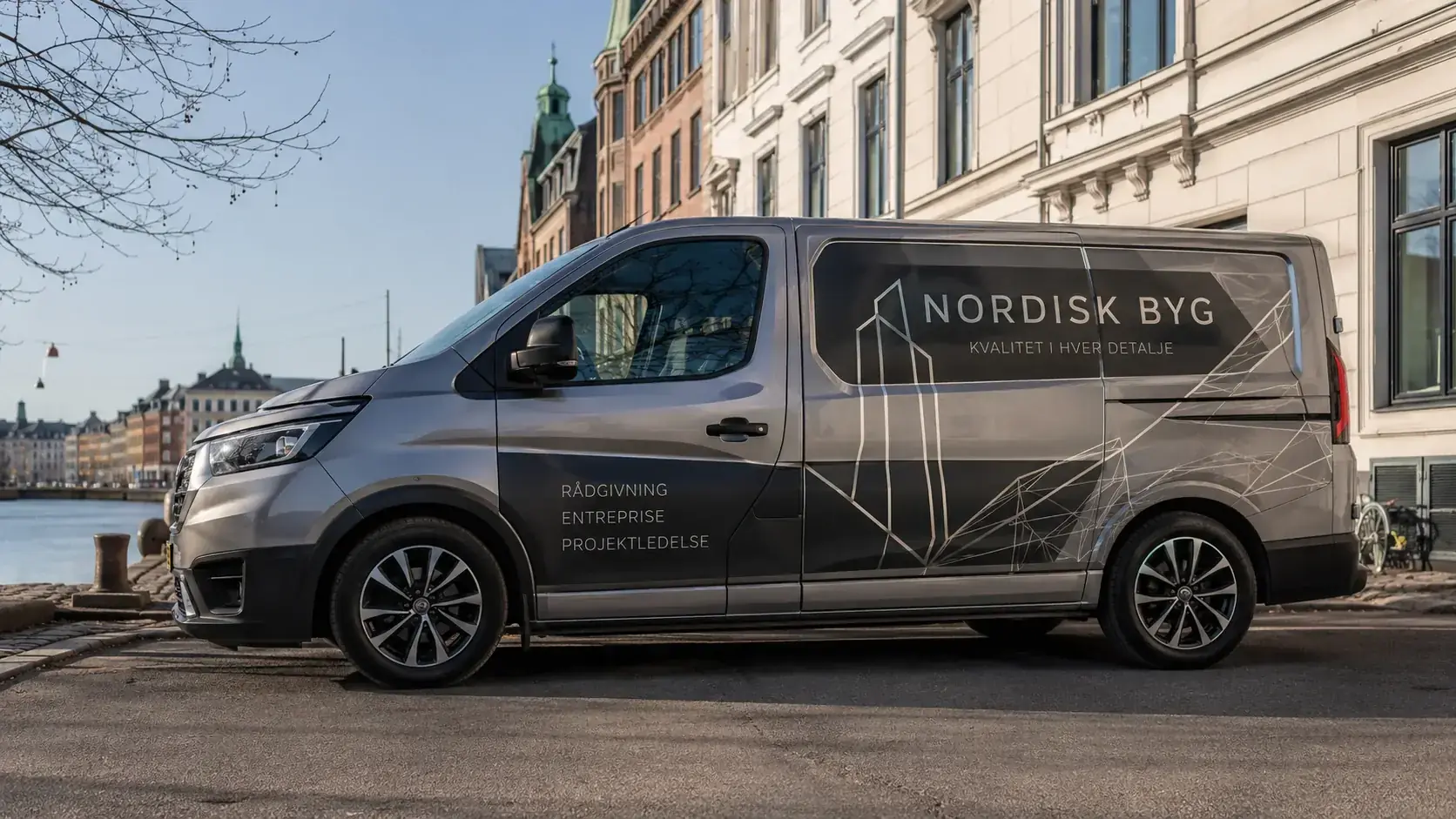 Firmabil med bilreklame parkeret i københavnsk miljø — folie og dekor
